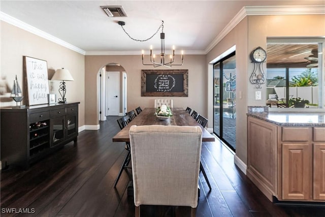 dining room with visible vents, a notable chandelier, dark wood-style floors, arched walkways, and crown molding