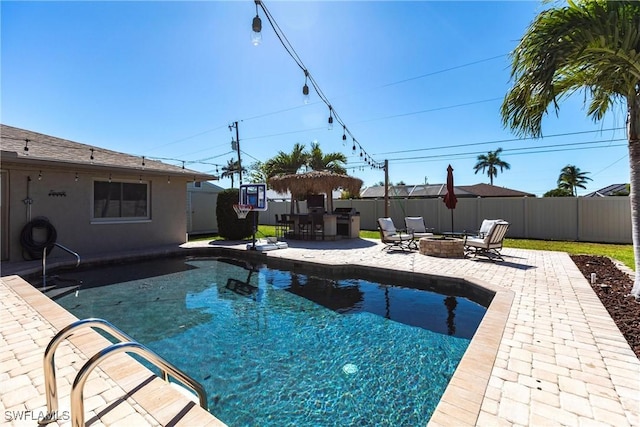 view of swimming pool featuring a fenced in pool, a fenced backyard, a fire pit, a patio area, and outdoor dry bar