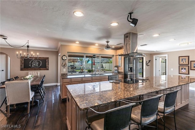 kitchen with arched walkways, a sink, stainless steel refrigerator with ice dispenser, black electric cooktop, and island range hood