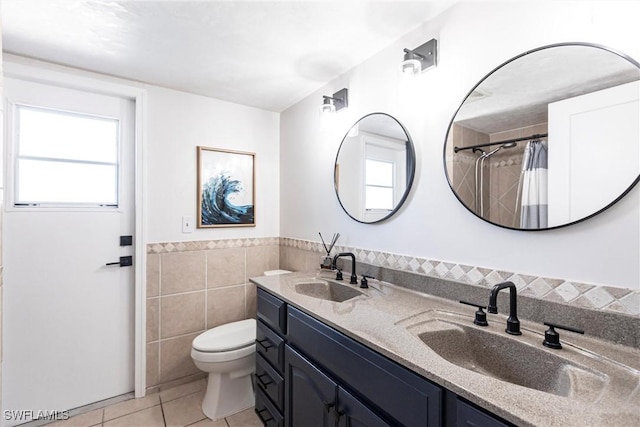 bathroom featuring tile patterned flooring, toilet, tile walls, and a sink