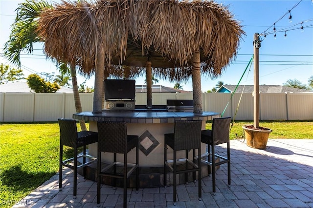 view of patio with outdoor wet bar, a grill, exterior kitchen, and a fenced backyard