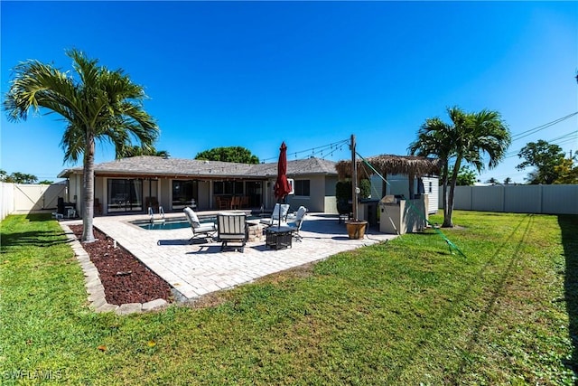 back of property featuring a fenced in pool, a fire pit, a lawn, a fenced backyard, and a patio area