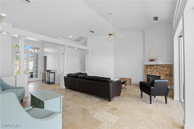 living room featuring visible vents, stone tile floors, a fireplace, and ornate columns