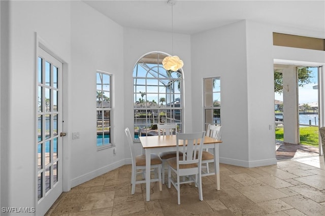 dining area with baseboards, plenty of natural light, and stone tile floors