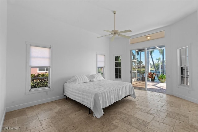 bedroom with stone tile flooring, multiple windows, baseboards, and access to outside