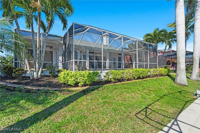 rear view of house featuring a lawn and glass enclosure