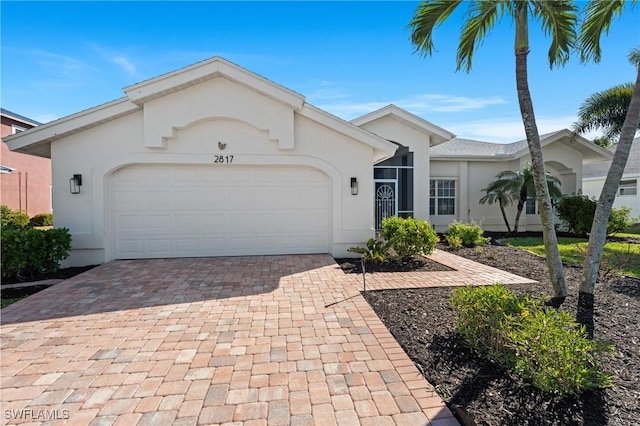 ranch-style home featuring stucco siding, decorative driveway, and a garage