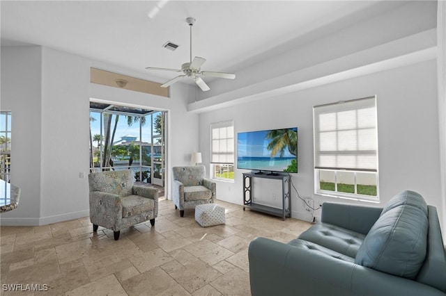 living area with stone tile floors, baseboards, visible vents, and ceiling fan