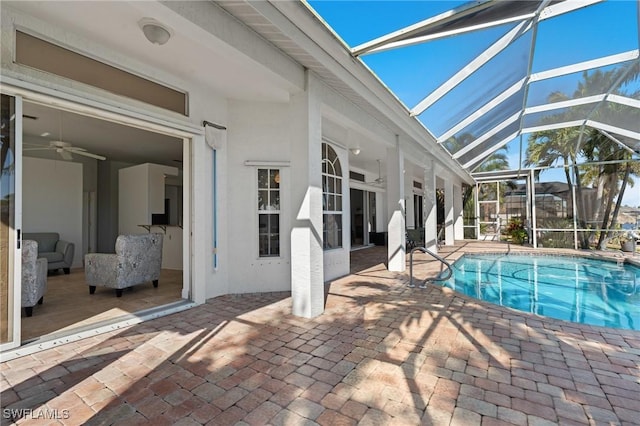 pool with glass enclosure, a patio, and a ceiling fan