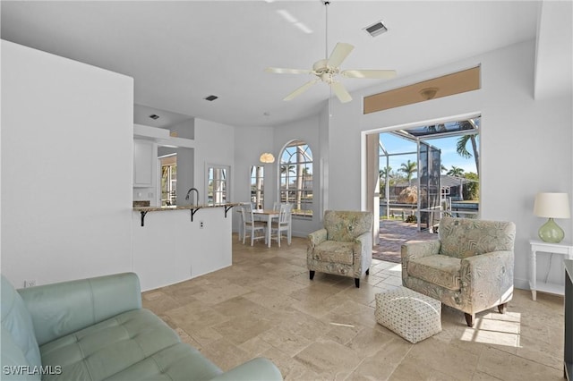 living room featuring visible vents, baseboards, a ceiling fan, and stone finish flooring