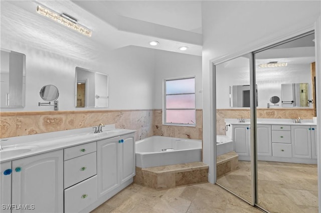 bathroom featuring a sink, a bath, and double vanity