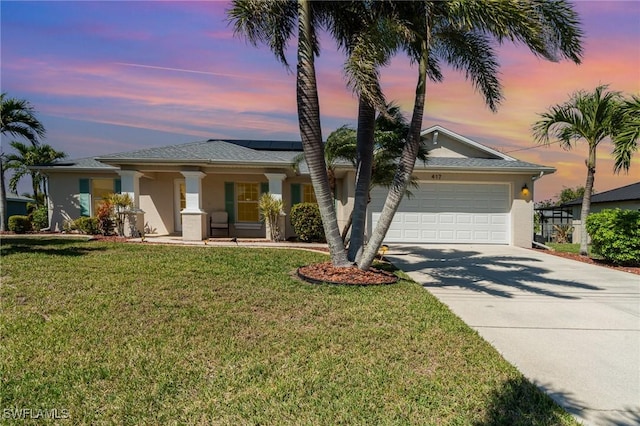 417 NW 3rd Ter, Cape Coral, FL 33993 - view of front facade with driveway, an attached garage, stucco siding, a front lawn, and roof mounted solar panels