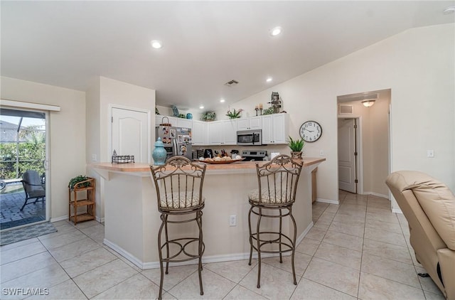 417 NW 3rd Ter, Cape Coral, FL 33993 - kitchen with a breakfast bar area, visible vents, lofted ceiling, stainless steel appliances, and white cabinets