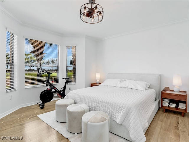 bedroom featuring an inviting chandelier, baseboards, light wood-type flooring, and ornamental molding