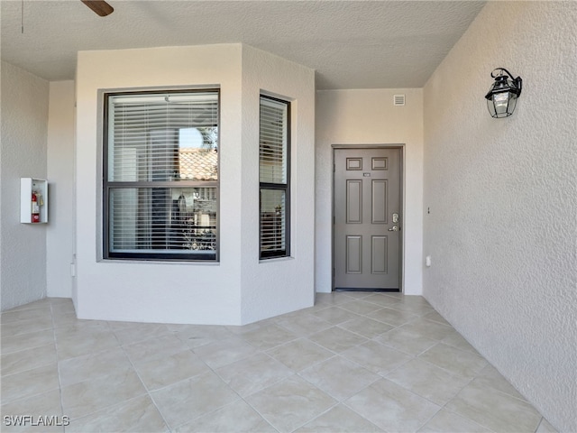 view of exterior entry with visible vents and stucco siding