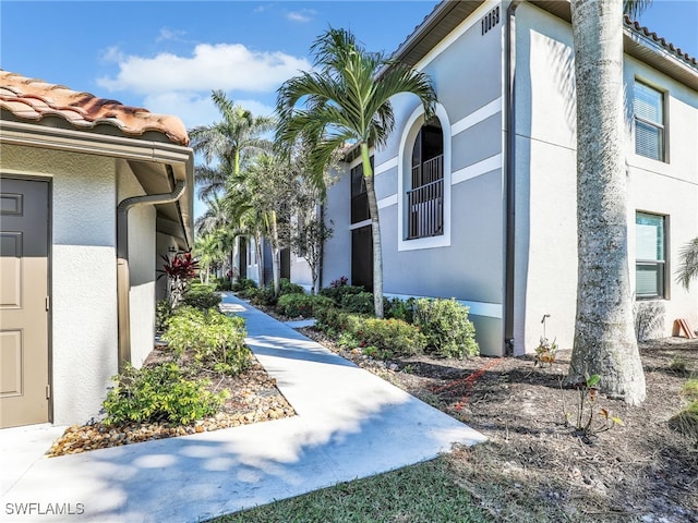 view of side of home with a tile roof and stucco siding