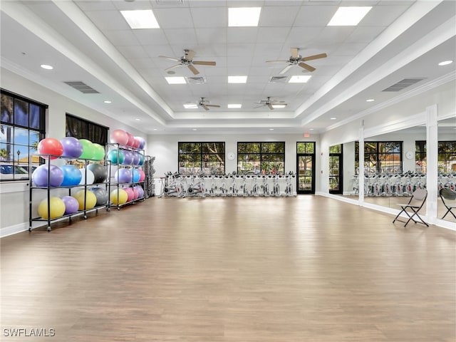 gym with a raised ceiling, wood finished floors, and visible vents