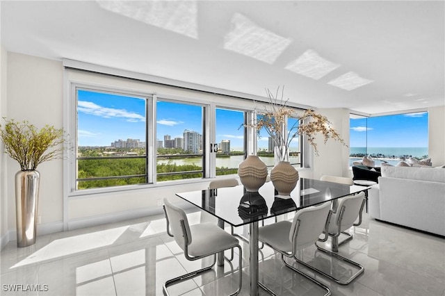 dining area with a city view, tile patterned floors, baseboards, and a water view