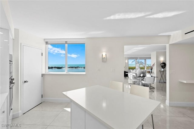 kitchen with white cabinetry, a kitchen island, light countertops, and baseboards