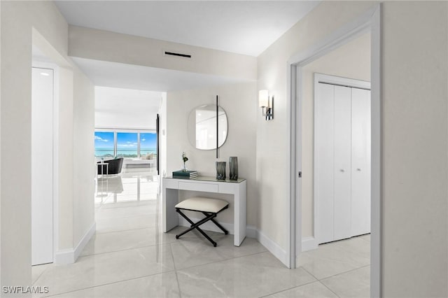 corridor with light tile patterned flooring, baseboards, and expansive windows