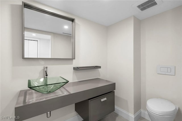 half bathroom featuring visible vents, toilet, baseboards, and a sink