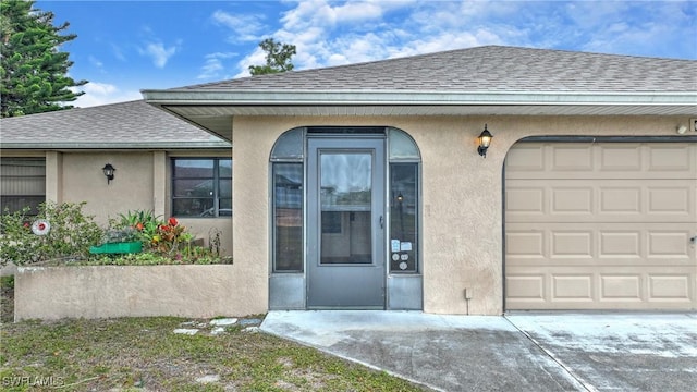 entrance to property with a shingled roof, an attached garage, and stucco siding