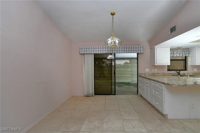 kitchen with visible vents, a sink, an inviting chandelier, white cabinets, and light stone countertops