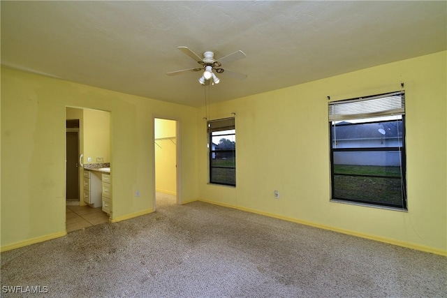 empty room featuring ceiling fan, baseboards, and light carpet