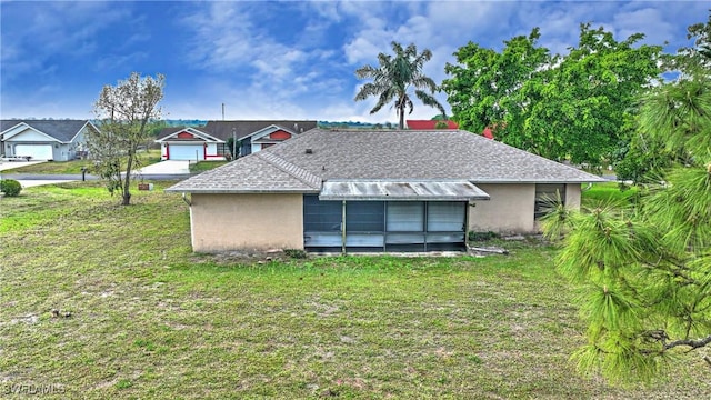 rear view of property featuring stucco siding, a yard, and roof with shingles