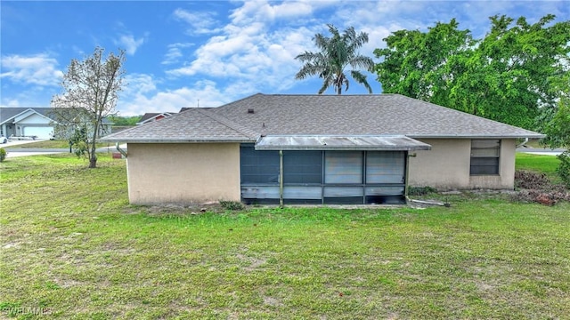 rear view of property with stucco siding, a lawn, and roof with shingles