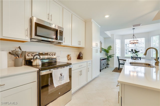 kitchen with light countertops, stainless steel appliances, light tile patterned flooring, white cabinetry, and a sink