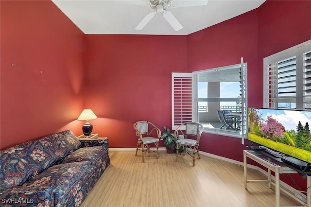 living area with baseboards, wood finished floors, and ceiling fan