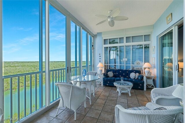 sunroom / solarium featuring plenty of natural light, a water view, and a ceiling fan