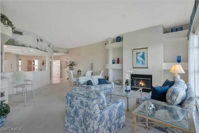 living area with visible vents and a glass covered fireplace