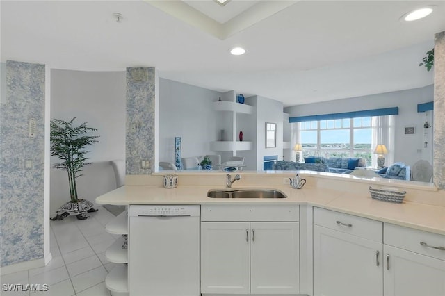 kitchen with open floor plan, light countertops, a sink, dishwasher, and white cabinets
