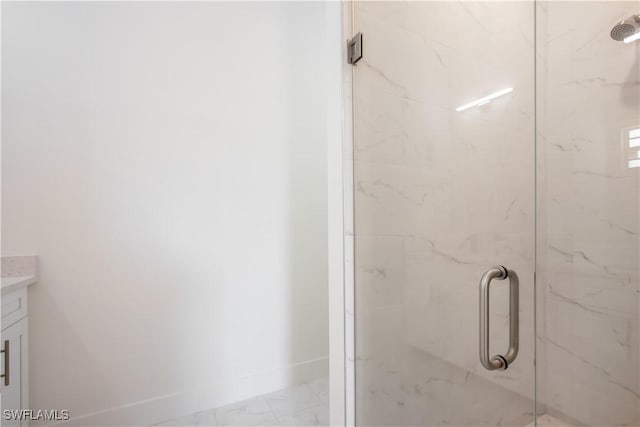 bathroom featuring a marble finish shower, baseboards, and vanity