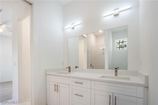 full bathroom with a shower stall, ceiling fan, double vanity, and a sink