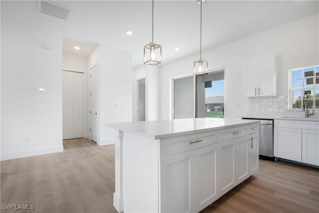 kitchen with a sink, dishwasher, light countertops, a center island, and light wood-style floors