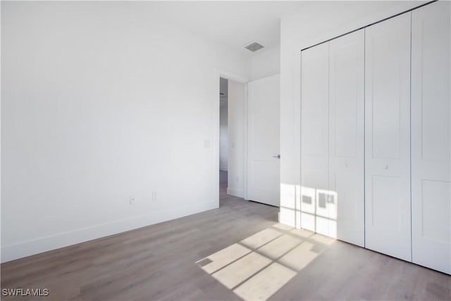 unfurnished bedroom featuring baseboards, visible vents, and wood finished floors