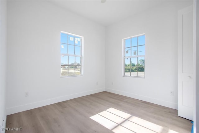 empty room with a wealth of natural light, baseboards, and wood finished floors