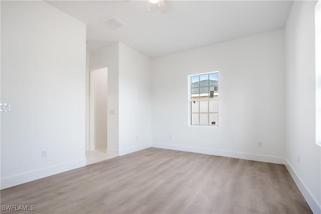 empty room with baseboards, visible vents, and wood finished floors