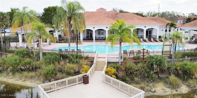 community pool featuring a patio area, stairs, and fence