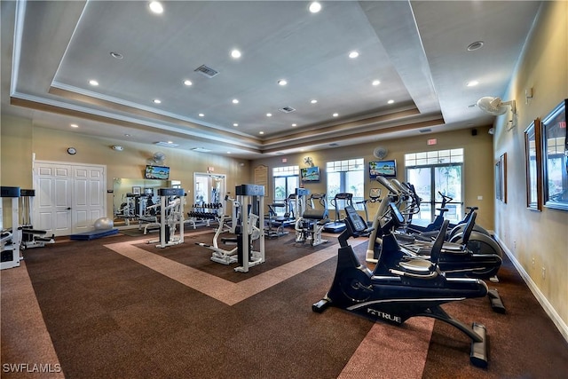 exercise room with visible vents, a raised ceiling, baseboards, and ornamental molding