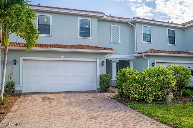 mediterranean / spanish-style home with stucco siding, a tile roof, decorative driveway, and a garage