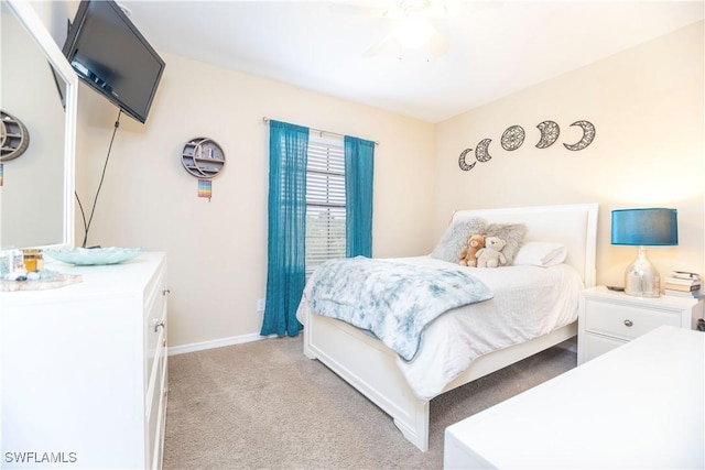 bedroom featuring light colored carpet, a ceiling fan, and baseboards