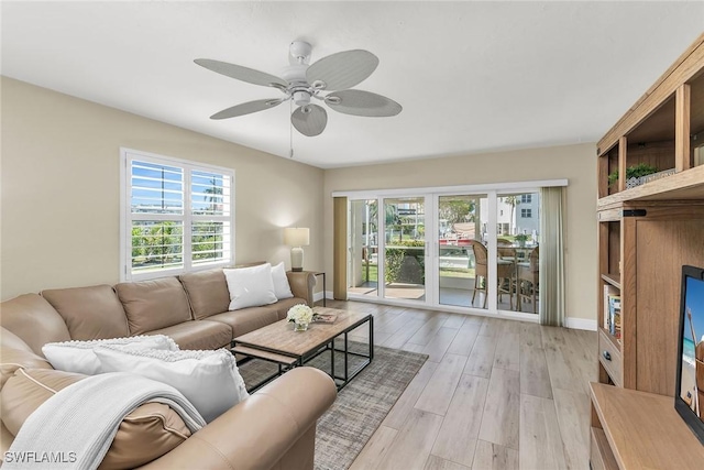 living room with a ceiling fan, light wood-type flooring, and baseboards