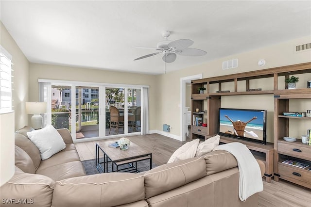 living room featuring ceiling fan, visible vents, baseboards, and wood finished floors