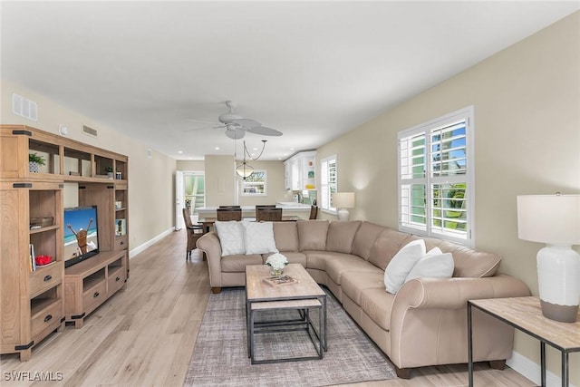 living area with visible vents, baseboards, light wood-style floors, and a ceiling fan