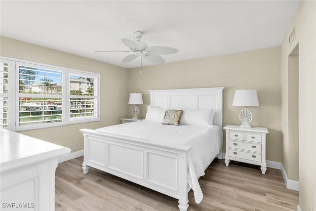 bedroom featuring light wood-type flooring, baseboards, visible vents, and a ceiling fan