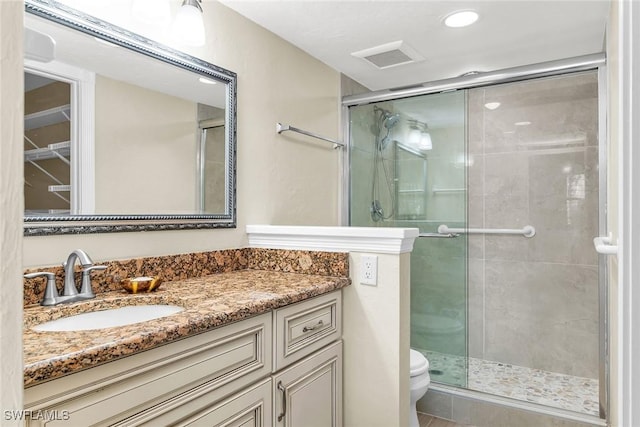 full bath with visible vents, toilet, a stall shower, and vanity